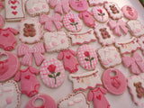 23sweets.com Collection of decorative pink and white cookies shaped like baby-themed items on a white background