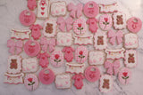 23sweets.com Collection of decorative pink and white cookies shaped like baby-themed items on a white background