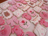 23sweets.com Collection of decorative pink and white cookies shaped like baby-themed items on a white background