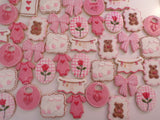 23sweets.com Collection of decorative pink and white cookies shaped like baby-themed items on a white background