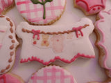 23sweets.com Collection of decorative pink and white cookies shaped like baby-themed items on a white background