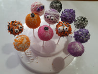 Colorful Halloween cake pops with decorative toppings on a white plate, by 23sweets.com