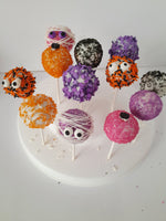 Colorful Halloween cake pops with decorative toppings on a white plate, by 23sweets.com