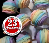 Rainbow-striped chocolate-covered cake pops on wooden sticks, with a circular '23 Sweets' logo overlay in the lower left.