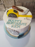 Birthday cake with tools and 'Happy Birthday Ken' text on a white plate.