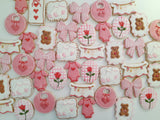 23sweets.com Collection of decorative pink and white cookies shaped like baby-themed items on a white background