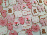 23sweets.com Collection of decorative pink and white cookies shaped like baby-themed items on a white background