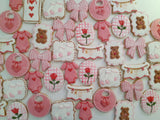 23sweets.com Collection of decorative pink and white cookies shaped like baby-themed items on a white background