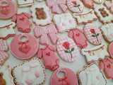 23sweets.com Collection of decorative pink and white cookies shaped like baby-themed items on a white background