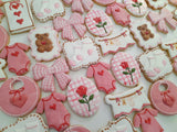 23sweets.com Collection of decorative pink and white cookies shaped like baby-themed items on a white background