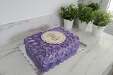 Purple rosette cake with a white plaque on a white background