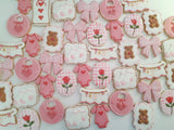 23sweets.com Collection of decorative pink and white cookies shaped like baby-themed items on a white background