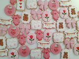 23sweets.com Collection of decorative pink and white cookies shaped like baby-themed items on a white background