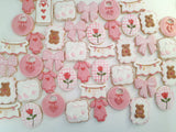 23sweets.com Collection of decorative pink and white cookies shaped like baby-themed items on a white background