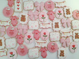 23sweets.com Collection of decorative pink and white cookies shaped like baby-themed items on a white background